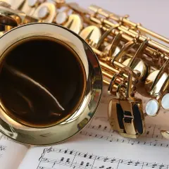 Złoty saksofon leży na nutach. Ten instrument dęty, jak wszystkie instrumenty dęte, jest gotowy do wydobycia pięknych dźwięków.