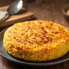 Un délicieux riso al salto, un gâteau de riz doré et croustillant, servi sur une assiette grise.