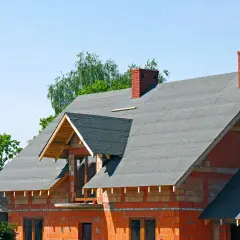 Budowa domu w toku. Na dachu widać już ułożoną papę, która chroni konstrukcję przed deszczem.