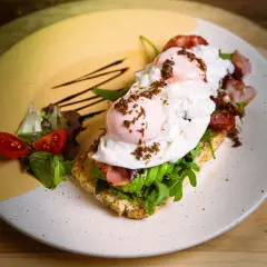 Tostada con aguacate, huevo escalfado y bacon, perfecta para un all day brunch. Acompañada de tomates cherry y rúcula.
