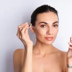 Kobieta aplikuje na twarz serum z peptydami. Skóra wygląda na nawilżoną i promienną.