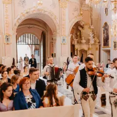 Muzycy grają pieśń na wejście w kościele. W tle para młoda wchodzi do świątyni.