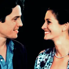 Uśmiechnięta obsada Notting Hill: Hugh Grant i Julia Roberts patrzą na siebie z czułością.