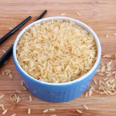 Ein blauer Napf mit hellem Reis, daneben schwarze Stäbchen. Der Unterschied Basmati und Parboiled Reis wird hier visuell dargestellt.