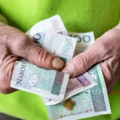 Dłonie trzymają polskie banknoty. Czy to już przyszła renta socjalna 2026?