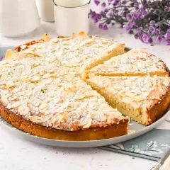 Tarta de almendras, espolvoreada con azúcar glas y almendras laminadas, lista para ser servida.
