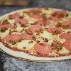 Gotowa do pieczenia pizza z salami, mozzarellą i grzybami. Idealna na kolację po włosku.