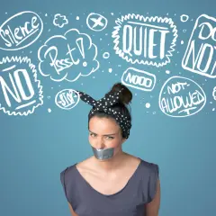 Kobieta z zaklejoną taśmą ustami, otoczona chmurkami z napisami "Silence", "Quiet", "No", "Stop", symbolizującymi tłumienie emocji.
