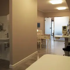 Gabinet okulistyczny z aparaturą medyczną, biurkiem i umywalką.