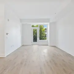 Amplio salón diáfano con suelo de madera clara y puerta acristalada que da a un balcón con vistas a árboles. Ideal para vender piso heredado antes de 5 años.