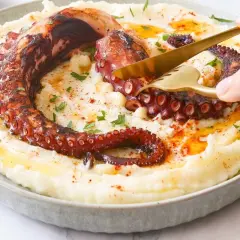 Un delicioso pulpo a la brasa, con sus tentáculos crujientes, servido sobre un puré cremoso.