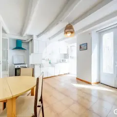 Cocina luminosa en una casa en Sallent, con vigas de madera en el techo, mesa de comedor y puertas acristaladas.