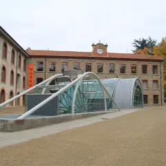 Edificio moderno con struttura in vetro e metallo accanto a un edificio storico, con insegna "MUSEO" a **stia Arezzo**.