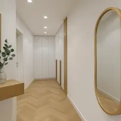 Eleganckie lustro owalne w drewnianej ramie odbija światło w nowoczesnym korytarzu z parkietem w jodełkę.