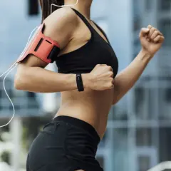 Kobieta w sportowym stroju biegnie, angażując liczne mięśnie. Widoczne ramiona, brzuch i nogi pracują intensywnie.
