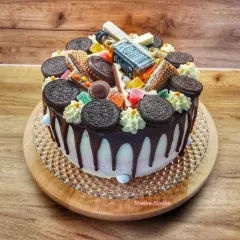 Tort z polewą czarny drip, ozdobiony ciasteczkami Oreo, waflem i mini buteleczką Jack Daniel's.