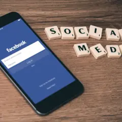 Telefon z ekranem logowania Facebooka i kafelki z napisem "SOCIAL MEDIA". Dowiedz się, jak zmienić email na FB.