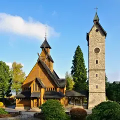 Drewniany kościółek i kamienna wieża z zegarem, jedne z głównych karpacz atrakcje w okolicy, otoczone zielenią.