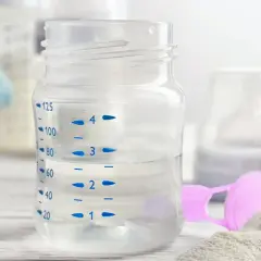 Biberon con acqua per latte in polvere, pronto per essere preparato.