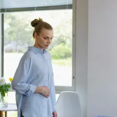 Kvinna med handen på magen, kanske oroande över klamydia symtom.