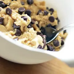 En skål med chokladkakdeg, redo för ett cookie dough recept. En sked sticker upp ur den ljuvliga smeten.