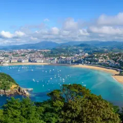 Widok na zatokę La Concha w San Sebastián. Widać miasto, plażę, góry i liczne łodzie na wodzie. Idealne miejsce na loty widokowe.