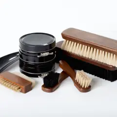 Ensemble d'outils cordonnier : cirages noirs, brosses en bois de différentes tailles et un chausse-pied.
