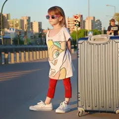Dziewczynka z walizką czeka na wakacyjną przygodę. Może już niedługo przeczyta wierszyki o wakacjach krótkie, siedząc na plaży.