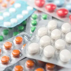 Opakowania leków, w tym białe tabletki podobne do Duspatalin, zielone, pomarańczowe i czerwone pigułki.