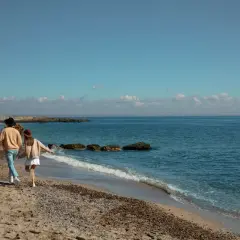 Para z psem spaceruje po plaży w Mielnie. To świetne mielno atrakcje poza sezonem, gdy jest spokojniej i można cieszyć się naturą.