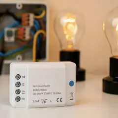 Interruptor Wi-Fi inteligente junto a bombillas encendidas y caja de conexiones.
