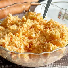Pyszna surówka z marchewki z chrzanem, przygotowana z tartych marchewek i doprawiona ostrym chrzanem, w szklanej misie.