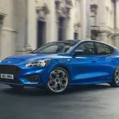Ford Focus blu in movimento, disponibile con motori a benzina e diesel, sfreccia in una strada cittadina.