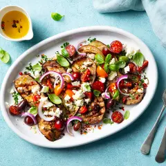 Gegrillte Auberginenscheiben mit Tomaten, Oliven, Feta und Basilikum – ein köstliches Beispiel für mediterrane Rezepte.