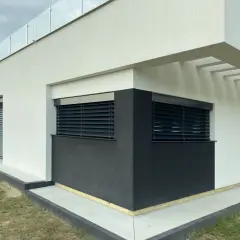 Nowoczesny budynek z czarnymi żaluzjami fasadowymi, które zapewniają komfortową regulację światła.