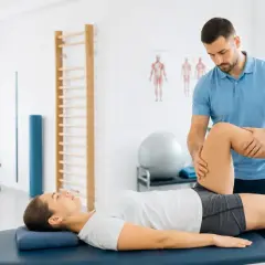 Fizjoterapeuta wykonuje ćwiczenia podczas sesji fizjoterapii ortopedycznej, pomagając pacjentce w rehabilitacji.