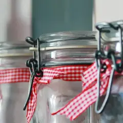 Słoiki z nalewkami, ozdobione czerwoną kratką. Czy nalewka może sfermentować? Zależy od składników i sposobu przygotowania.