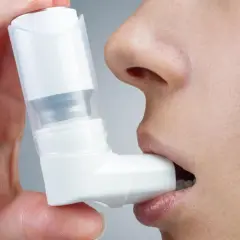 Dłoń trzyma inhalator Ventolin przy ustach. Szybka ulga w astmie.