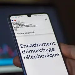 Un smartphone affiche le site du Ministère de l'Économie, avec le titre "Encadrement démarchage téléphonique".