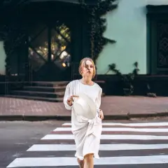 Dziewczyna w białej sukience i kapeluszu przechodzi przez pasy. Stylizacja sugeruje, że to marka MSGM.