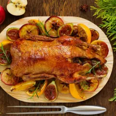 Pieczona kaczka w pomarańczach, jabłkach i figach, ozdobiona rozmarynem. Aromatyczne danie świąteczne.