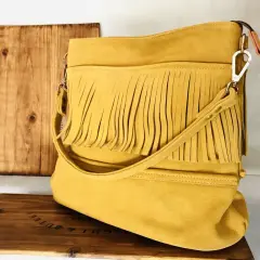 Bolso amarillo con flecos, de ante o serraje, sobre una caja de madera.