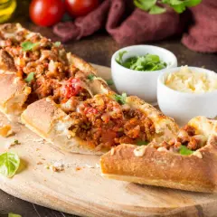 Une baguette farcie généreusement avec une sauce à la viande savoureuse et du fromage fondant, prête à être dégustée.