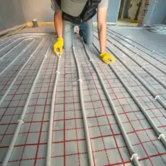 Instalator układa rury do ogrzewania podłogowego. Dokładna ilość metrów rury na m2 podłogówki zależy od projektu.