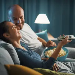 Para spędza miły wieczór, śmiejąc się i jedząc popcorn. Idealny czas na fajne filmy romantyczne na wieczór.