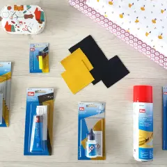 Matériel pour enlever colle sur tissu polyester : tubes de colle textile, cuir, spray adhésif, marqueur effaçable et tissu imprimé.