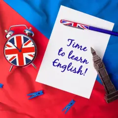 Budzik z flagą Wielkiej Brytanii, długopis i napis "Time to learn English!" na tle brytyjskich barw. Sebastian, czas na naukę!