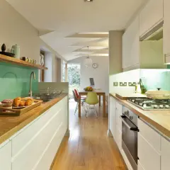 Cocina moderna con encimeras de madera, salpicadero verde menta y electrodomésticos integrados. Ideas para como diseñar una cocina funcional y estilosa.