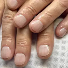 Dłonie z zadbanymi paznokciami po zabiegu manicure męski. Paznokcie są czyste, wypielęgnowane i lekko nabłyszczone.