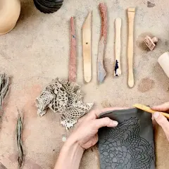 Mani che lavorano con il das adulti, creando un motivo a pizzo su argilla con strumenti da scultore.